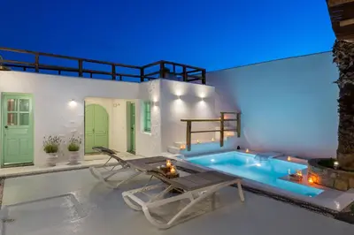 a swimming pool with a table and a chair next to a house at Dipagio Origin Villa in Lachania