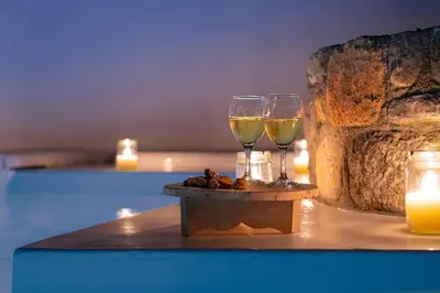 two glasses of wine sitting on a table with candles at Dipagio Origin Villa in Lachania