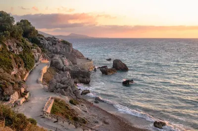 a beach with rocks and the ocean at sunset at Modern Quiet Apartment in the Center of Rhodes in Rhodes Town