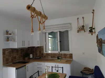 a kitchen with white cabinets and a table and a window at Galazia Thea Apartments in Archangelos