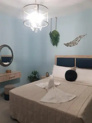 a bedroom with a bed with a mirror and a chandelier at Galazia Thea Apartments in Archangelos