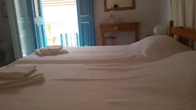 a bedroom with a white bed with a window at Albatros in Symi