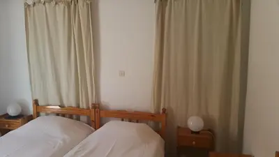 a bedroom with two beds and two lamps and curtains at Albatros in Symi