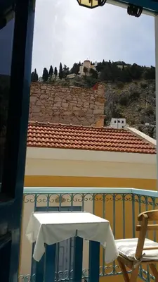 a table and chair on a balcony with a view at Albatros in Symi