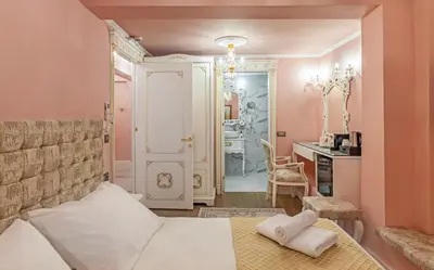 a bedroom with pink walls and a bed and a desk at Via Villa Iliotti Rhodos in Rhodes Town