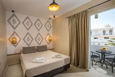 a bedroom with a bed and a table and a window at Atma Beach Rooms & Suites in Faliraki
