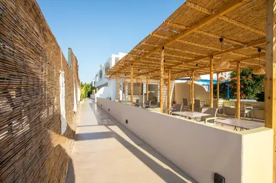 an outdoor patio of a building with tables and chairs at Atma Beach Rooms & Suites in Faliraki