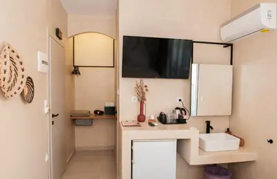a small kitchen with a sink and a tv on the wall at Atma Beach Rooms & Suites in Faliraki