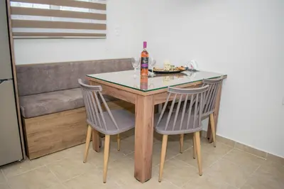 a dining room table with two chairs and a bottle of alcohol at Golden sunrise stegna in Archangelos