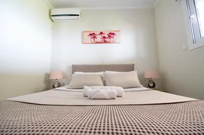 a bedroom with a large white bed with two lamps at Golden sunrise stegna in Archangelos