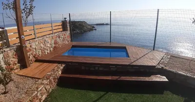 a swimming pool with a wooden deck and a fence at Golden sunrise stegna in Archangelos