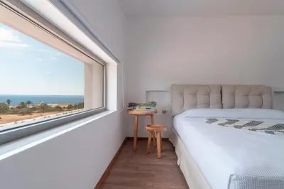 a bedroom with a large window with a bed and a table at Terra d'Oro Sea view villa with private pool in Kiotari