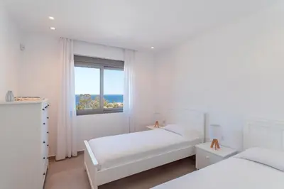 a white bedroom with two beds and a window at Terra d'Oro Sea view villa with private pool in Kiotari