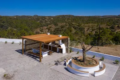 a pavilion with a table and a tree in a yard at Terra d'Oro Sea view villa with private pool in Kiotari