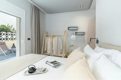 a white bedroom with a bed with a mirror at Elia & Anthos Deluxe Suites in Ixia