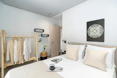 a bedroom with a white bed and clothing racks at Elia & Anthos Deluxe Suites in Ixia