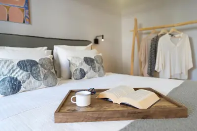 a tray with a book and a cup of coffee on a bed at Elia & Anthos Deluxe Suites in Ixia