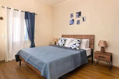 a bedroom with a bed with a blue blanket and a window at Rementzo Apartment in Symi