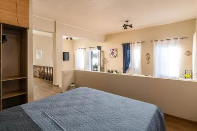 a bedroom with a blue bed and windows at Rementzo Apartment in Symi