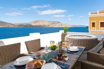a table on a balcony with a view of the ocean at Rementzo Apartment in Symi