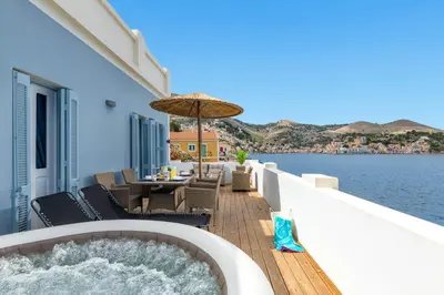 a hot tub on a deck next to the water at Rementzo Apartment in Symi