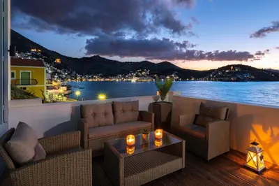 a balcony with couches and a view of the water at Rementzo Apartment in Symi