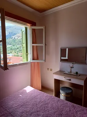 a bedroom with a bed and a desk and a window at Zoe Apartments in Symi