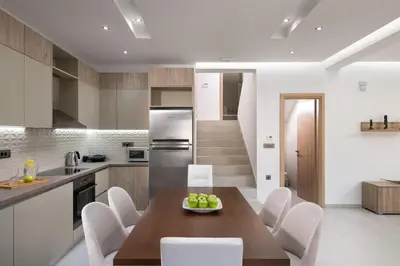 a kitchen with a wooden table and white chairs at Panthea Luxury Villa in Triánta