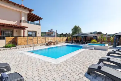 a swimming pool in a yard with chairs and a house at Panthea Luxury Villa in Triánta