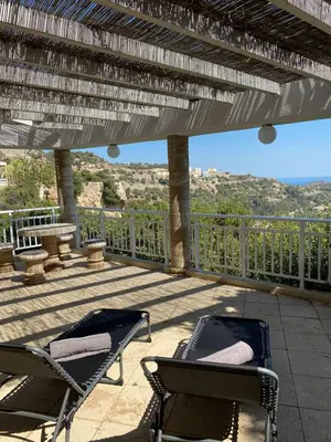 a patio with chairs and a deck with a view at Nostrana Village Apartments in Koskinou