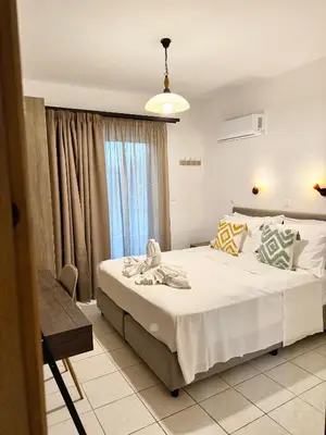 a bedroom with a large white bed and a window at Dorothea Apartments - Self-Catering Accommodation in Koskinou