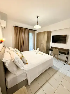 a bedroom with a white bed and a desk at Dorothea Apartments - Self-Catering Accommodation in Koskinou