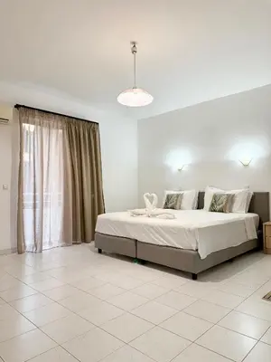 a bedroom with a bed and a large window at Dorothea Apartments - Self-Catering Accommodation in Koskinou