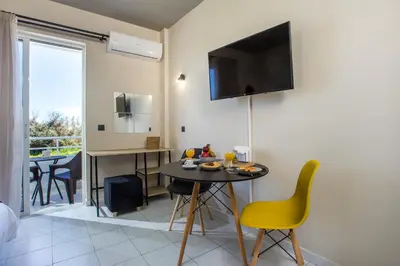 a living room with a table and a tv on the wall at Dorothea Apartments - Self-Catering Accommodation in Koskinou
