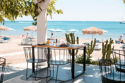 a table and chairs on the beach with the ocean at Cactus Suites in Faliraki