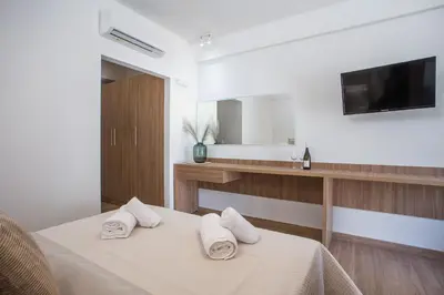 a white room with a bed with towels on it at Cactus Suites in Faliraki