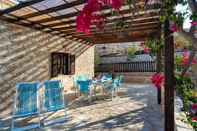 a patio with a table and chairs under a pergola at Villa Ftenagia in Halki