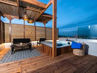 a wooden deck with a hot tub and a table at Lymberia Hotel in Faliraki
