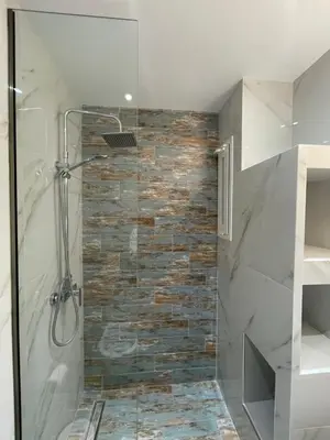 a bathroom with a shower with a stone wall at Skizenas Waterfront Apartments in Haraki