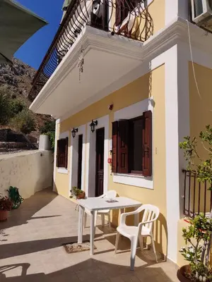 a patio with a white table and chairs in front of a house at Nikos and Eva Studios in Symi
