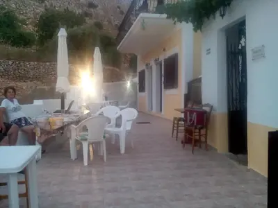 a woman sitting on a chair in a patio at Nikos and Eva Studios in Symi