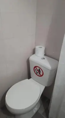 a bathroom with a white toilet with a sign on it at Traditional Stone house in Rhodes Town