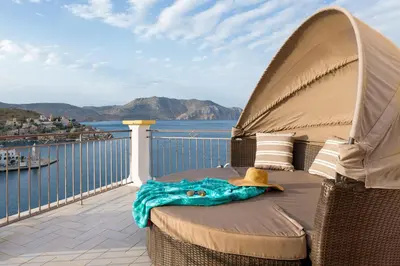 a chair on a balcony with a view of the water at Sea La Vie Villa Symi in Symi