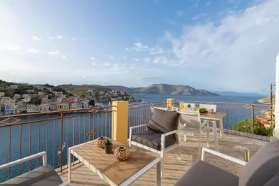 a balcony with a table and chairs and a view of the water at Sea La Vie Villa Symi in Symi