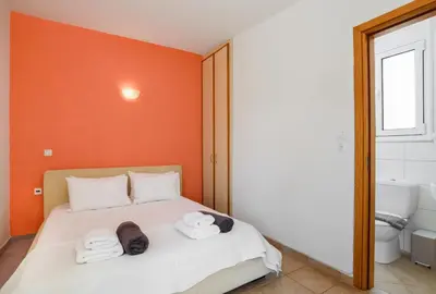 a bedroom with orange walls and a bed with towels at Blue Line Villa Lindos in Líndos