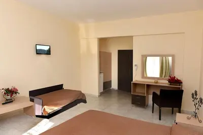 a bedroom with a bed and a desk and a mirror at Santa Helena Hotel in Ialyssos