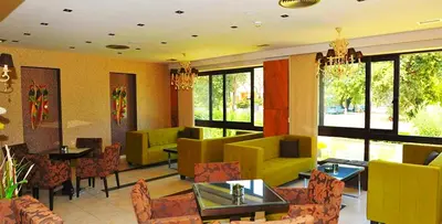 a restaurant with yellow furniture and tables and chairs at Santa Helena Hotel in Ialyssos