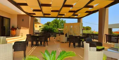 a patio with tables and chairs on a deck at Santa Helena Hotel in Ialyssos