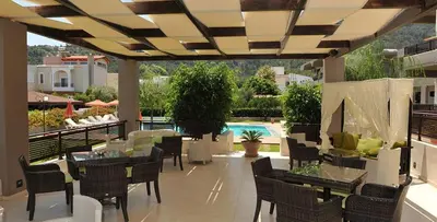 a patio with tables and chairs and a pool at Santa Helena Hotel in Ialyssos