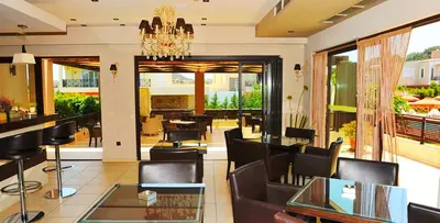 a restaurant with chairs and tables and a chandelier at Santa Helena Hotel in Ialyssos